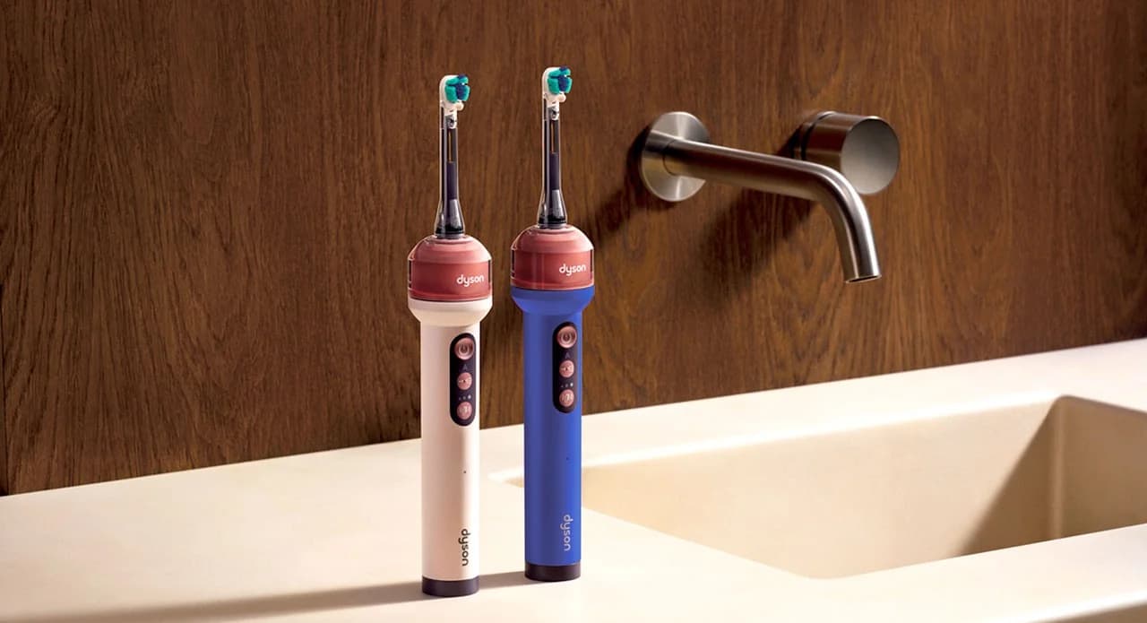Two Dyson CameraJet electric toothbrushes standing on a bathroom counter