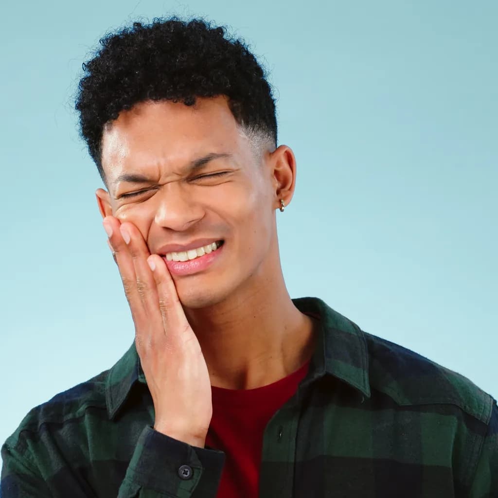 A young man pressing his hand against his jaw in pain